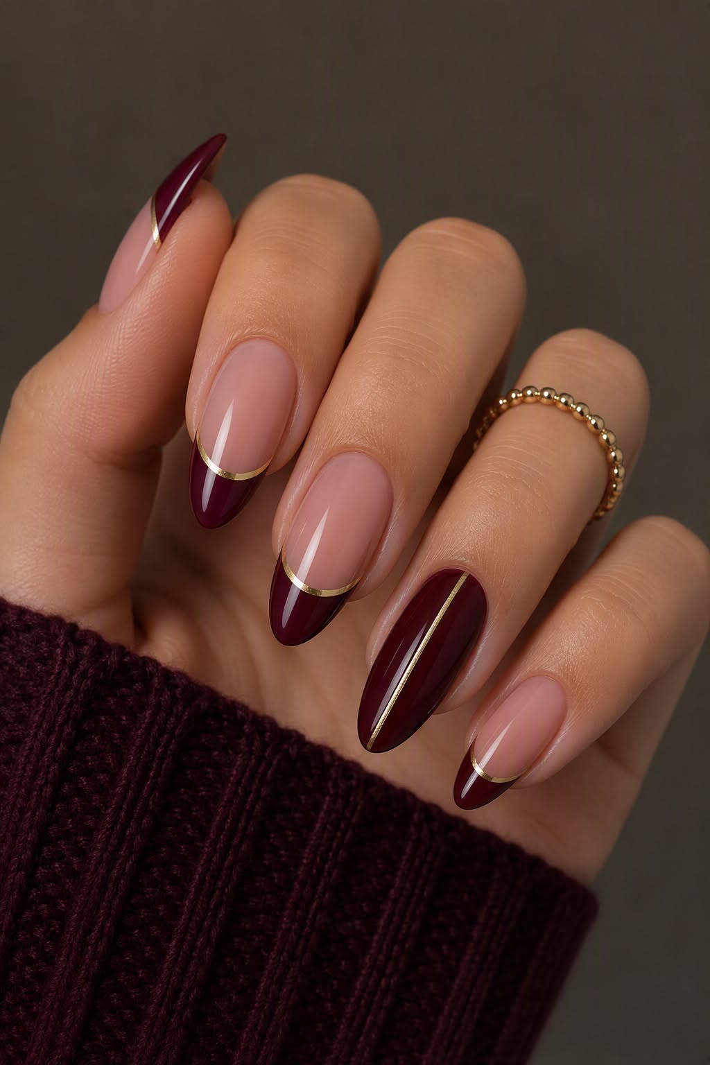 Nail art bordeaux avec détails dorés délicats