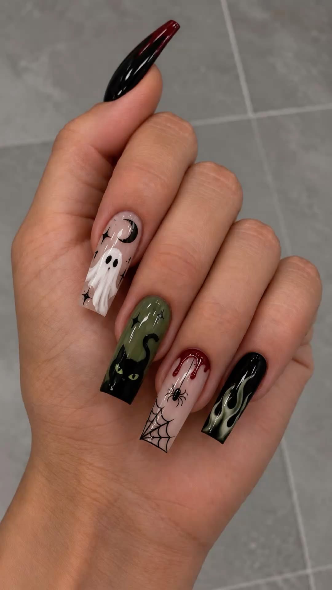 Long Halloween-themed nails with ghost, cat, spider, and flame designs.