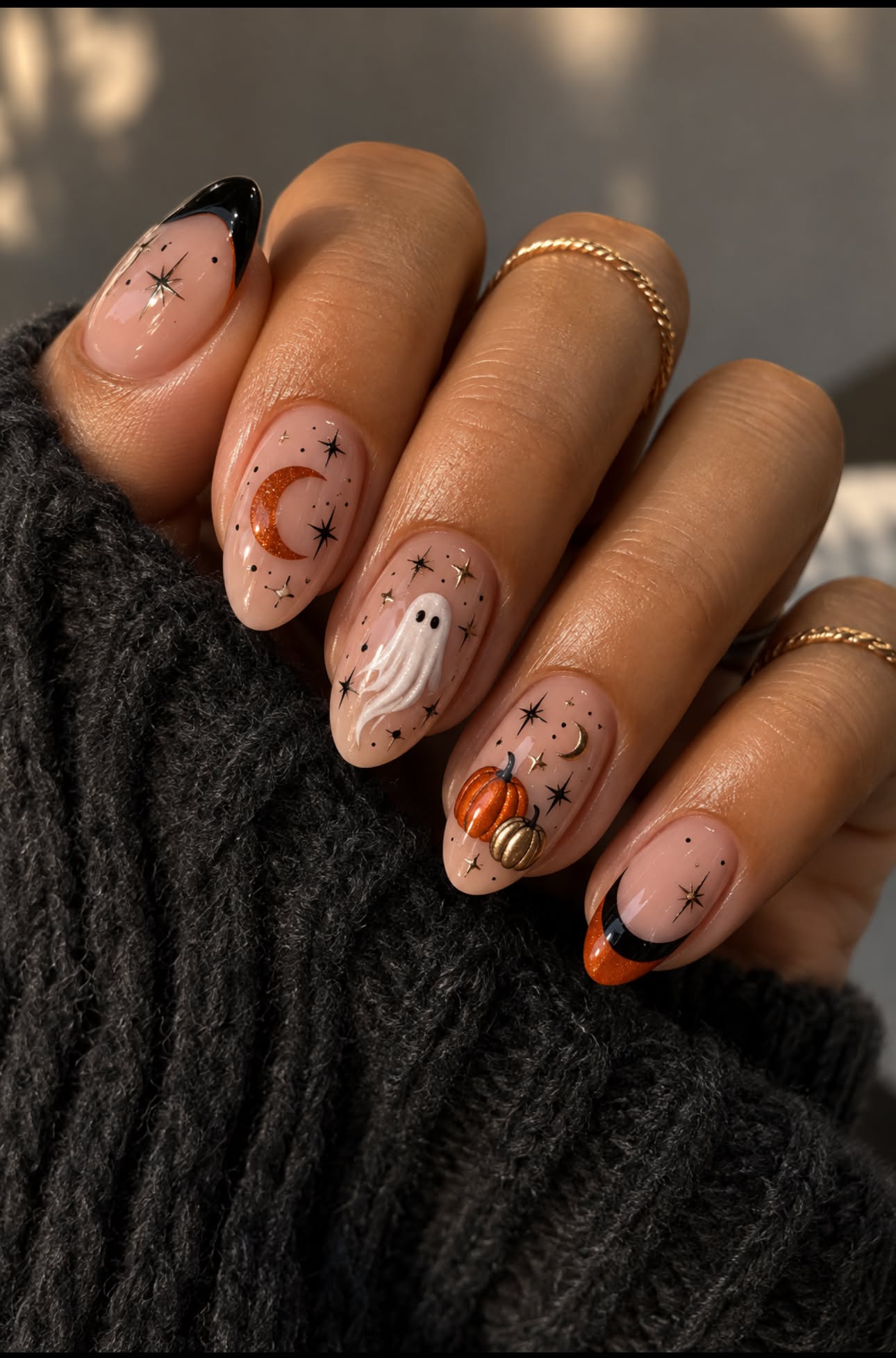 Nails decorated with Halloween-themed designs including a ghost, pumpkins, and crescent moons.