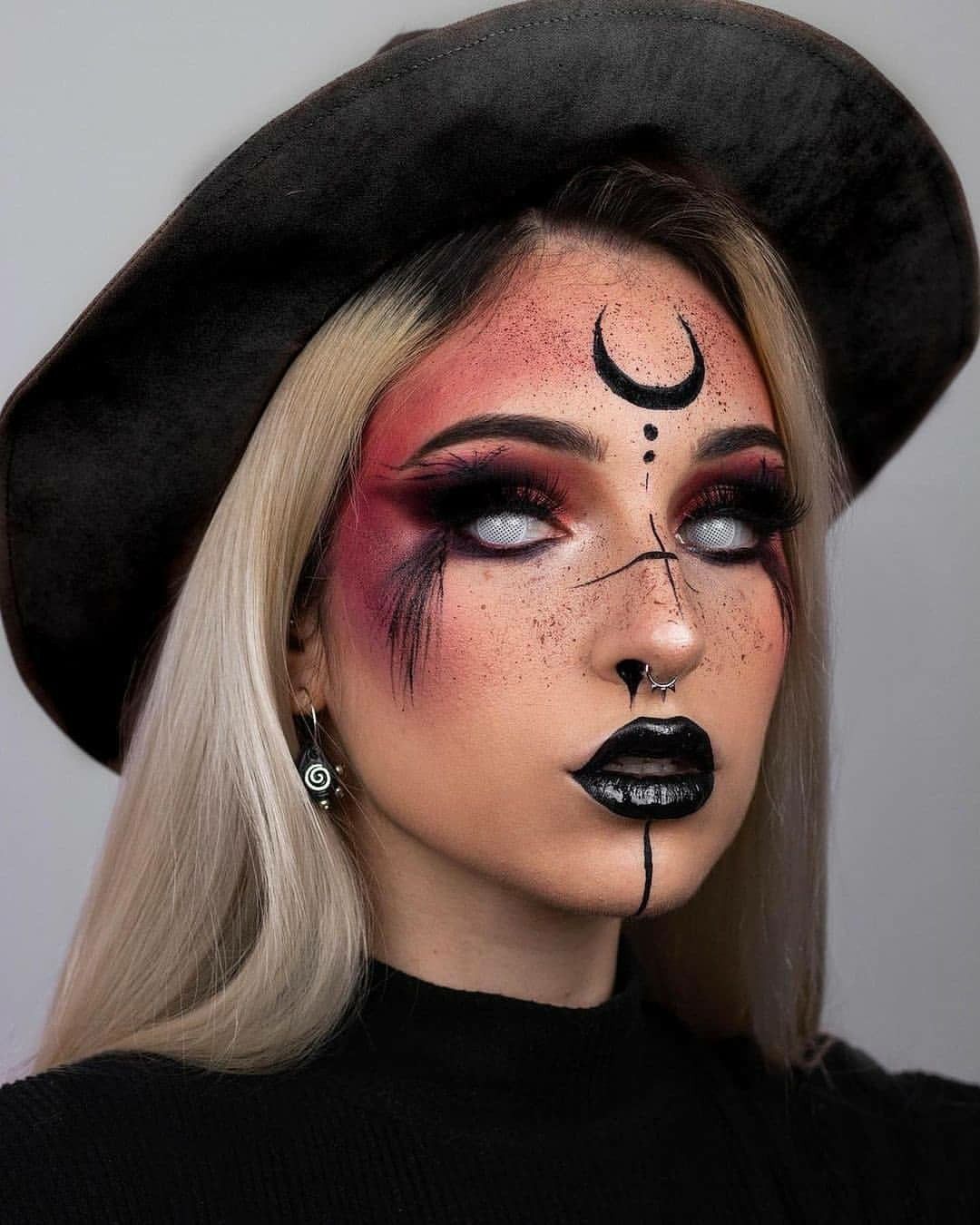 Visage maquillé avec des motifs noirs et rouges, yeux blancs, et chapeau noir.