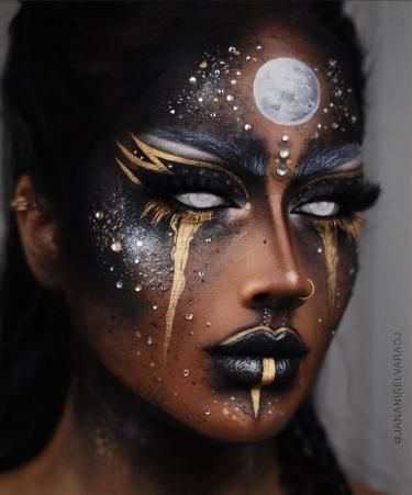 Visage maquillé en noir avec détails dorés et lune blanche sur le front.